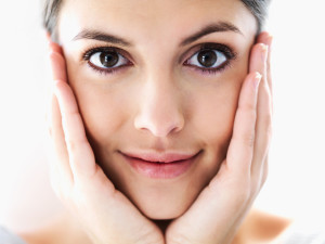 Closeup of a charming young girl holding her face with hands